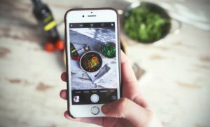 Bilden visar Influencer marketing. En influencer som fotograferar sin mat med mobilen för att publicera i sina sociala medier.