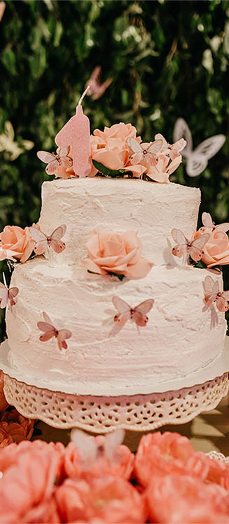 Rosa tårta täckt med smörkräm och rosa fjärilar.
