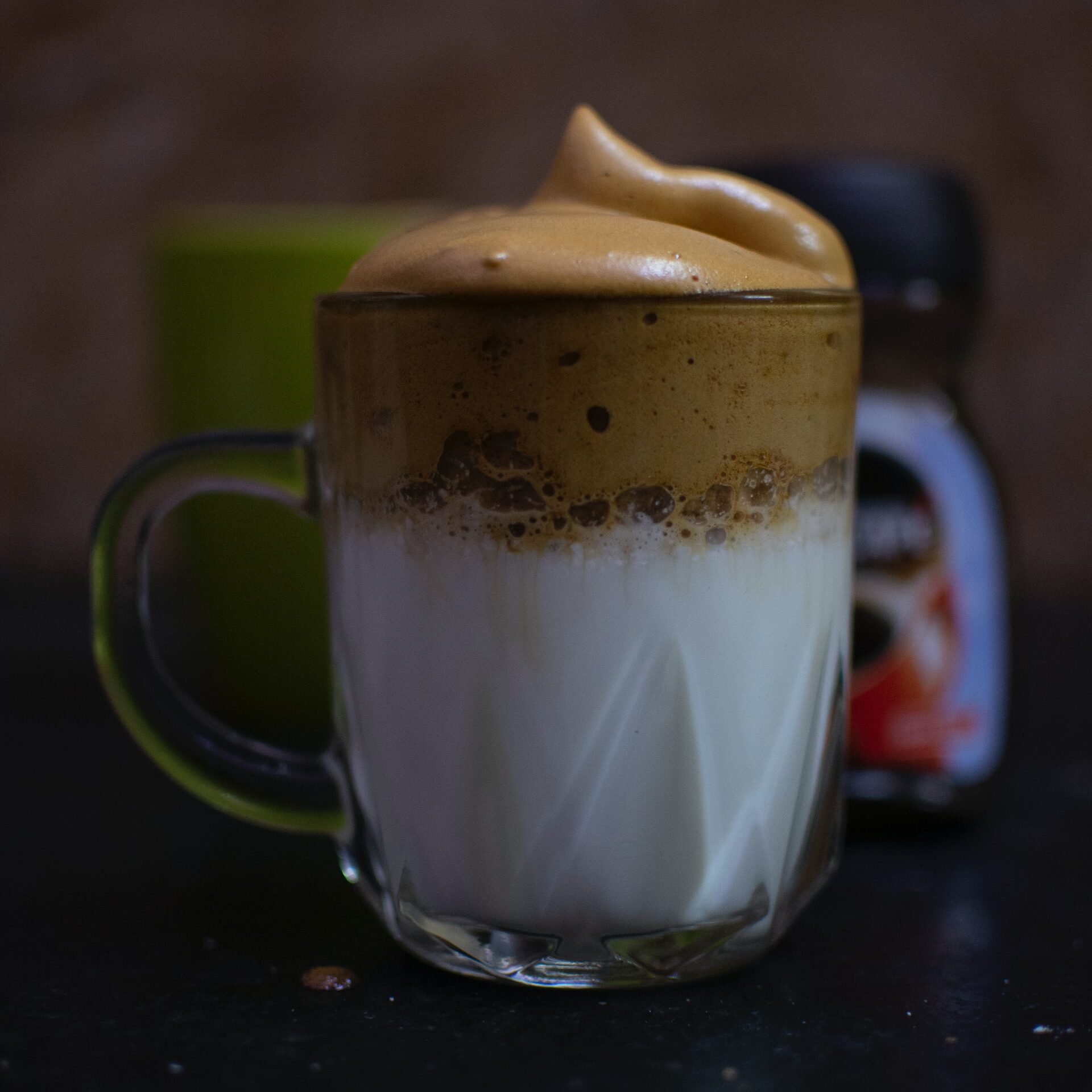 Glasmugg med mjölk och ljusbrunt fluffigt kaffeskum på toppen.